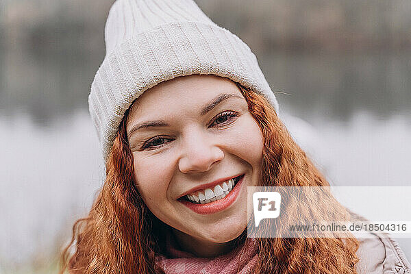 Curly redhead woman 30-35 in hat smiling