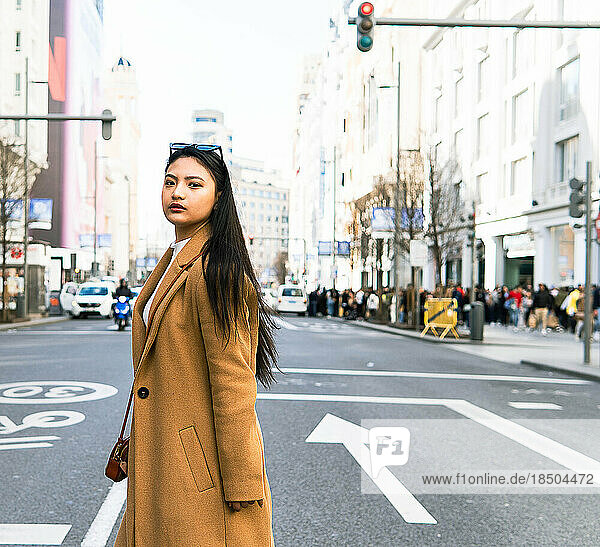 Asian girl crossing the road of Gran Via street in Madrid