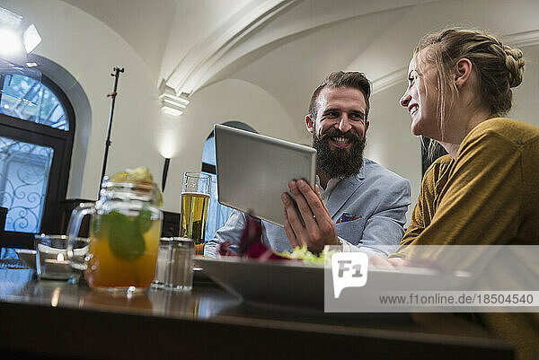 Smiling couple using digital tablet at restaurant