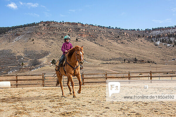 Girl practicing horseback riding in outdoor arena