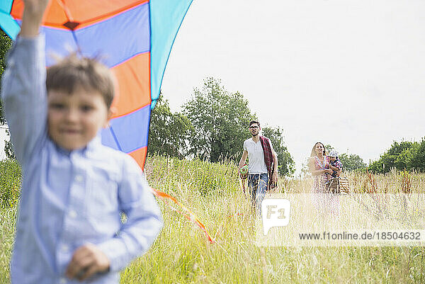 Family walking on meadow with picnic basket and kite in the countryside  Bavaria  Germany