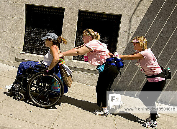 Teammates help push a woman in a wheelchair up San Francisco hills during a breast cancer walk.