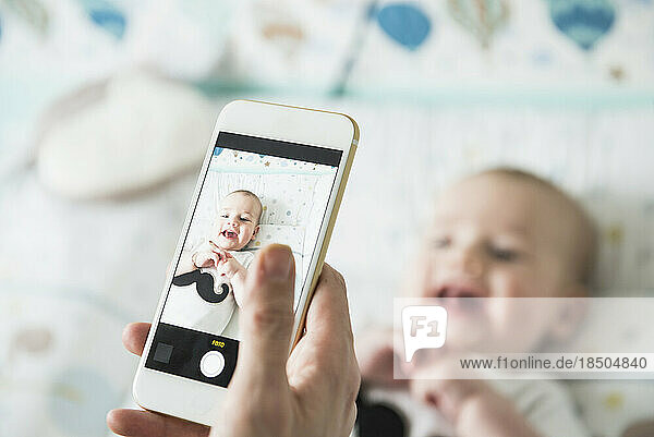 Mother photographing her baby with mobile phone
