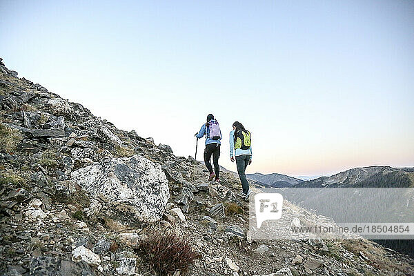 Two women trail runners push uphill in a Rocky Mountain early morning