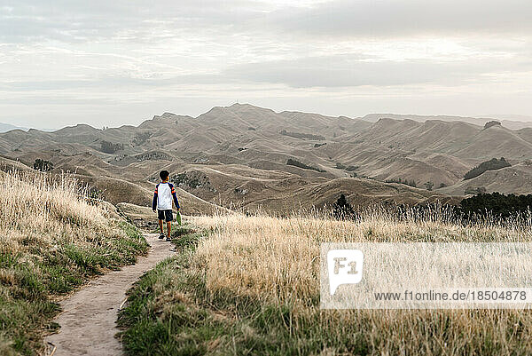 Preteen boy walking on a scenic path with mountains
