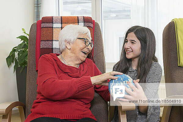 Girl playing bowling with senior woman in rest home