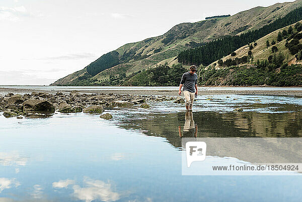 Man walking in water at low tide in New Zealand