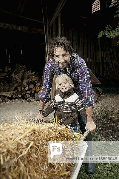 Father with his son pushing wheelbarrow in the farm  Bavaria  Germany