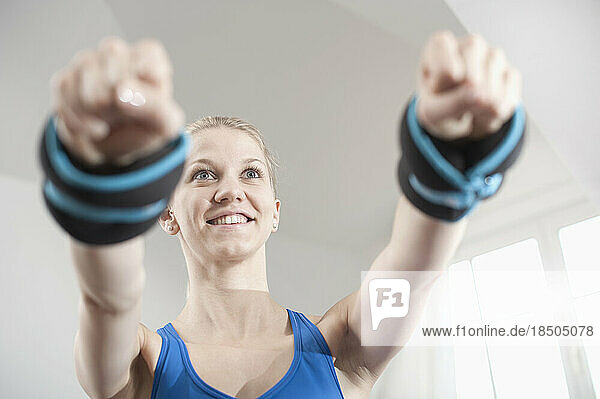 Young woman lifting weights in living room  Bavaria  Germany
