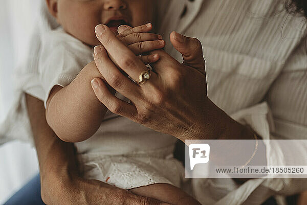 Close up of mother holding young daughter's fingers