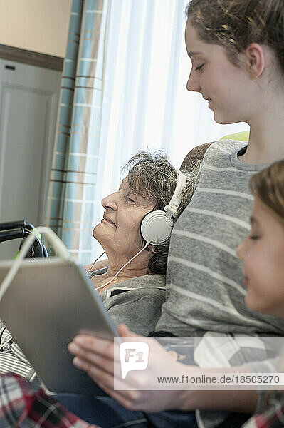 Senior woman listing music with grand children in rest home