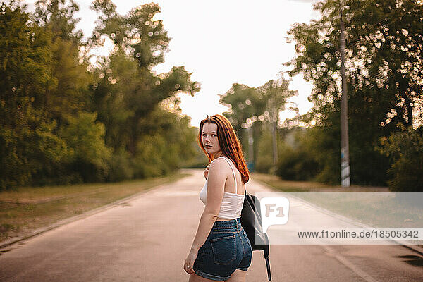 Young woman walking on country road during summer