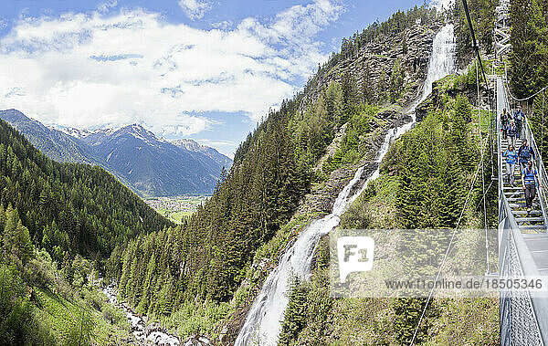 Group of climbers walking through suspension stairway by scenic Stuibenfall Waterfall  Otztal  Tyrol  Austria