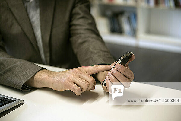 Mid section of a businessman using smart phone in an office  Bavaria  Germany