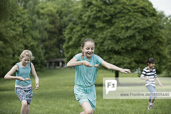 Group of girls competing in an egg-and-spoon race in a park  Munich  Bavaria  Germany