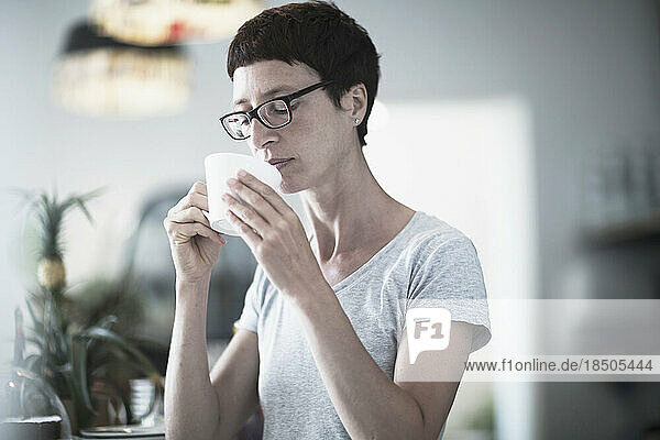Mature woman drinking coffee in the office  Freiburg im Breisgau  Baden-Württemberg  Germany