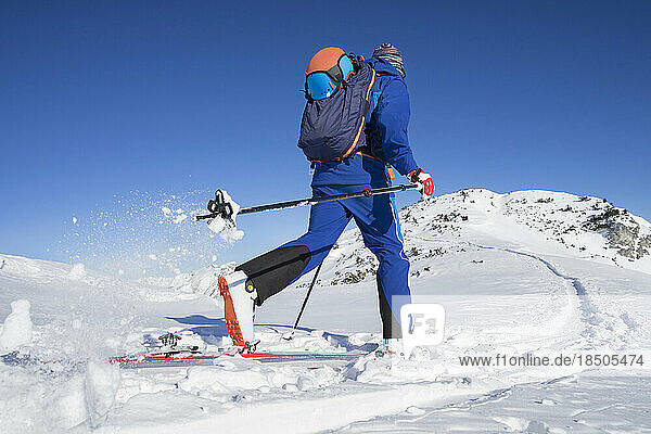 Rear view of skier walking on snow against sky