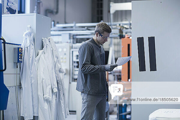 Young male engineer looking at report in an industrial plant  Freiburg Im Breisgau  Baden-Württemberg  Germany