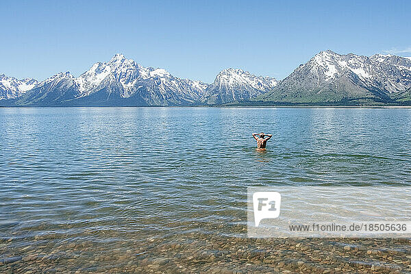 Teen boy swimming alone in alpine lake