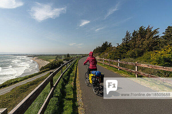 Cyclist woman riding a bike on road over the sea coast