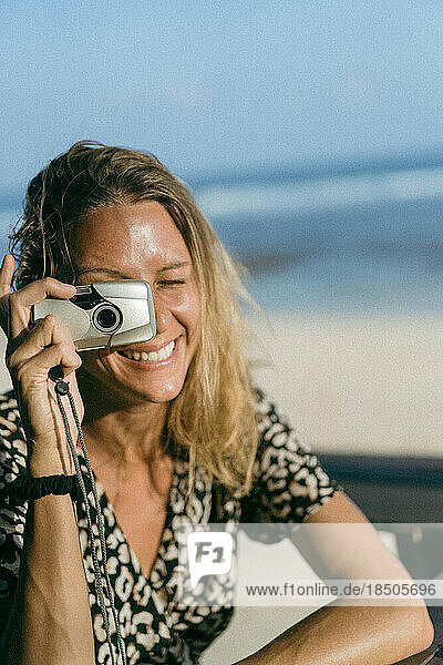 A woman takes a photo with a film camera.