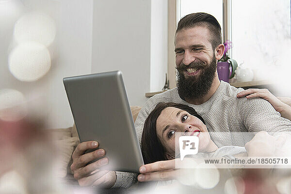 Couple watching digital tablet  relaxing on sofa