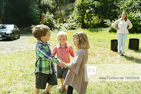 Portrait of three children holding hands and playing together
