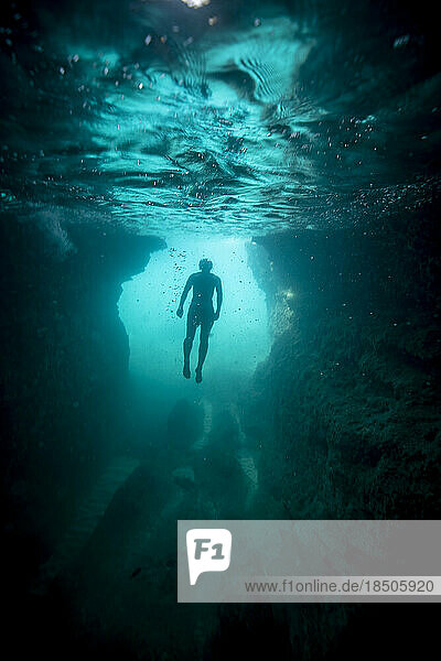 in the sea  a man floats in apnea just under the surface of the water