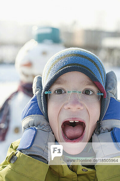 Portrait of boy covering his ears and screaming