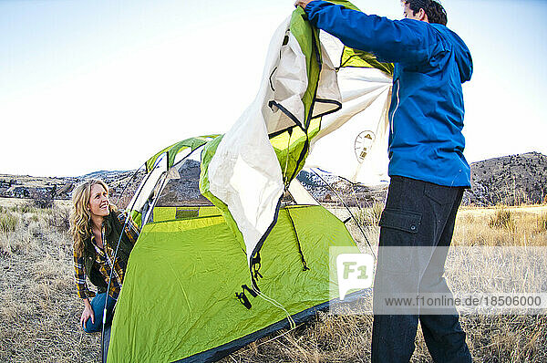 A couple putting their frost cover on their tent.