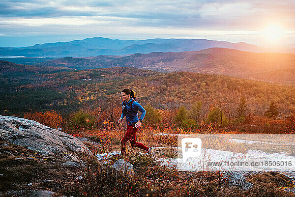 Woman trail running in mountains with foliage in autumn