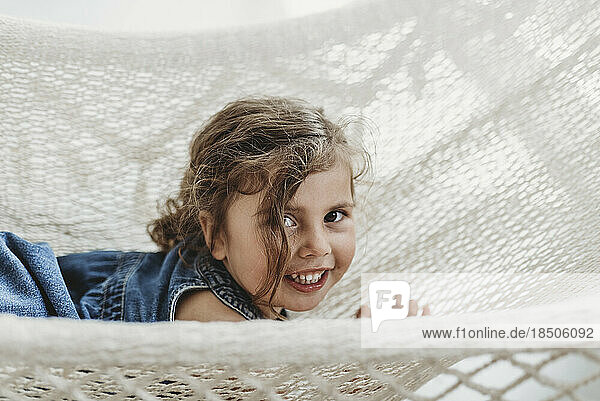 Young girl in hammock in studio smiling and looking at the camera