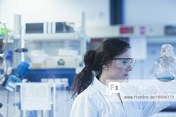 Young female scientist examining flask in a laboratory  Freiburg Im Breisgau  Baden-wuerttemberg  Germany