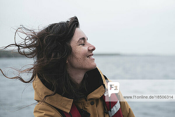 Profile of happy woman with freckles smiling on boat in Scotland