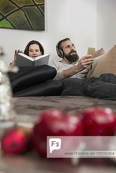 Woman reading diary while her husband listening music on headphones