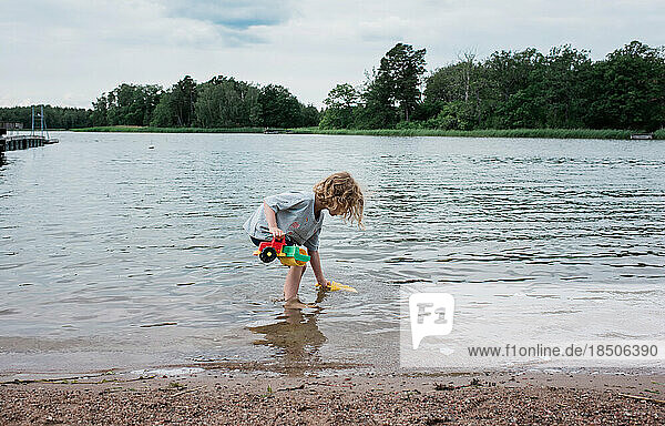 young girl playing with toys in the water at the beach in summer