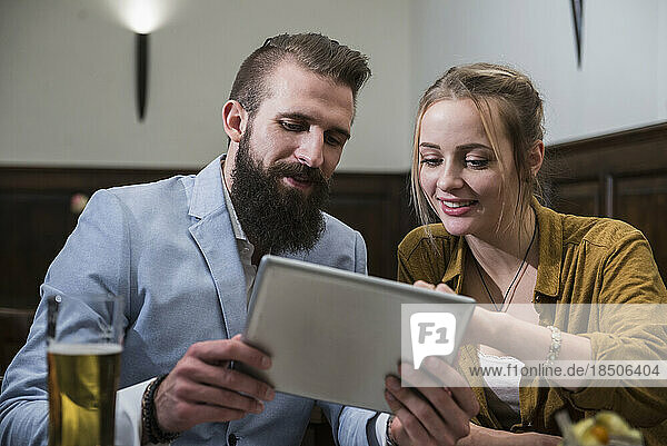 Couple using digital tablet at restaurant