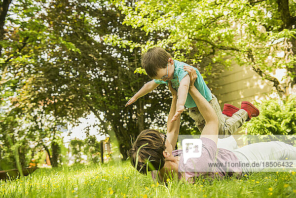 Mother lying in the garden and playing with her son