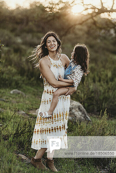 Full length view of mother and daughter embracing in sunny field