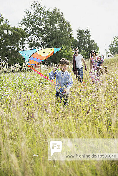 Family walking on meadow with picnic basket and kite in the countryside  Bavaria  Germany