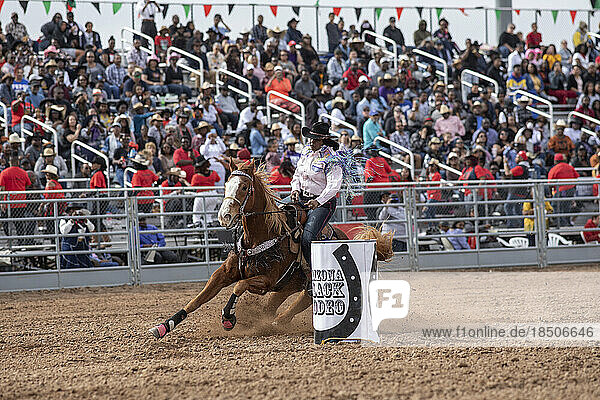 A cowgirl competes in the barrel racing event at the AZ black rodeo
