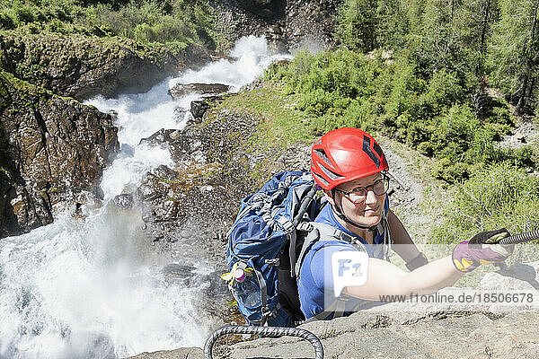 Woman climbing rock face via ferrata towards Stuibenfall Waterfall  Otztal  Tyrol  Austria