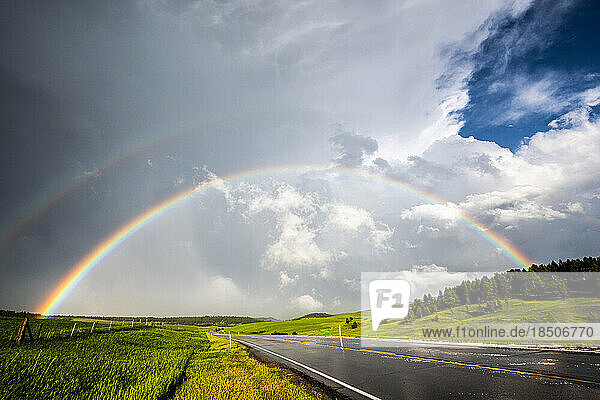 Double rainbow over road and green fields  cloudy sky