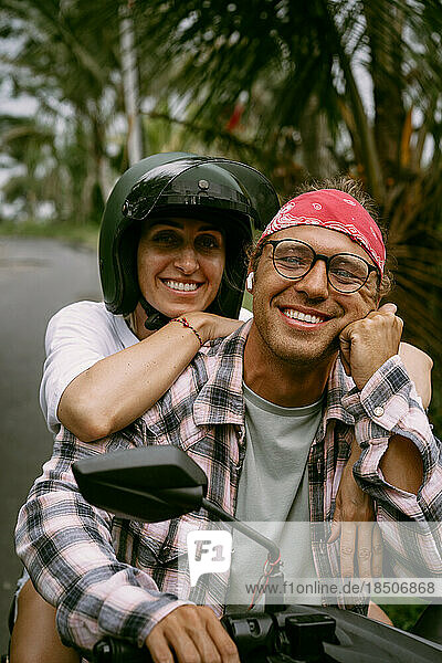 Young happy couple travel by bike in Bali.