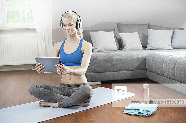 Young woman using digital tablet and listening to music in living room  Bavaria  Germany