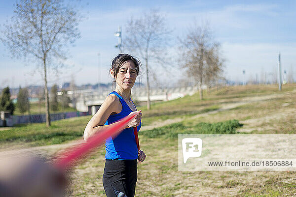 Female athlete exercising with resistance band on grassy field