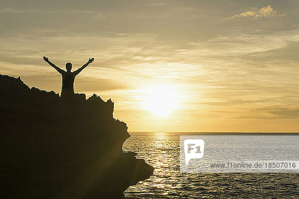 Silhouette of a man standing with arms outstretched on cliff during sunset  Nusa Lembongan  Bali  Indonesia