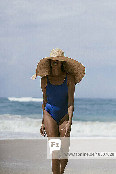 Young woman in a big straw hat on the ocean.