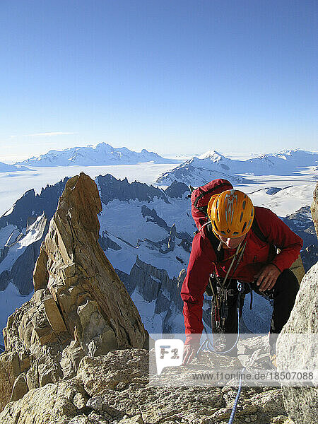 A climber climbs on the northwest ridge of Cerro Fitz Roy  with Volcan Lautaro and the southern Patagonia Icecap is in the backg