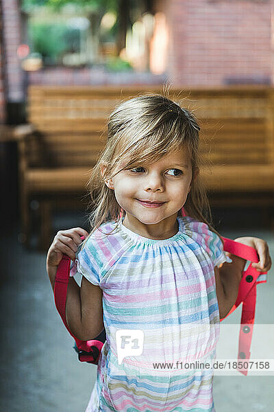 Preschool aged girl wearing backpack outside